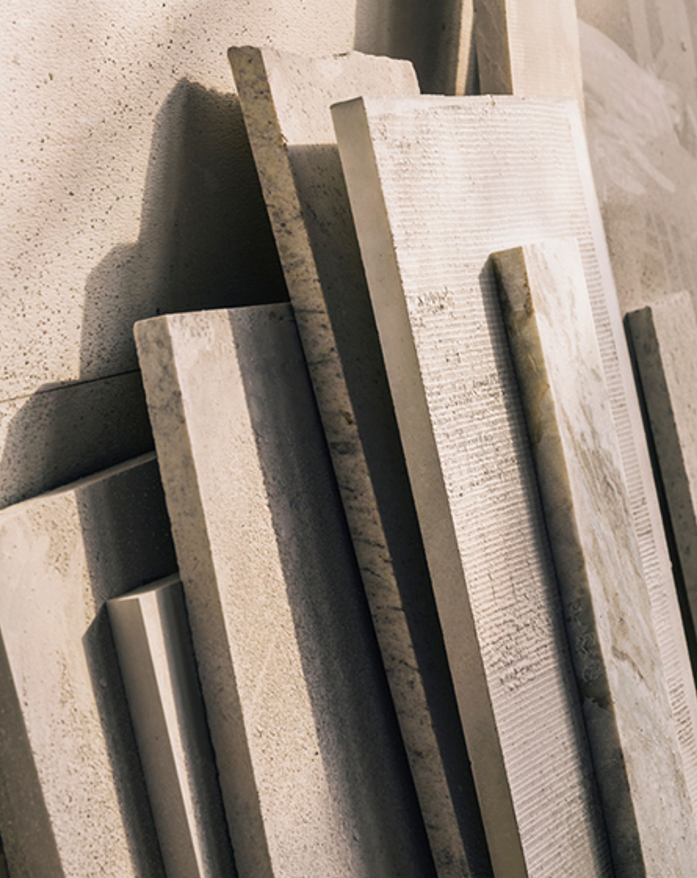 Varying planks of pale coloured wood stacked vertically against a wall